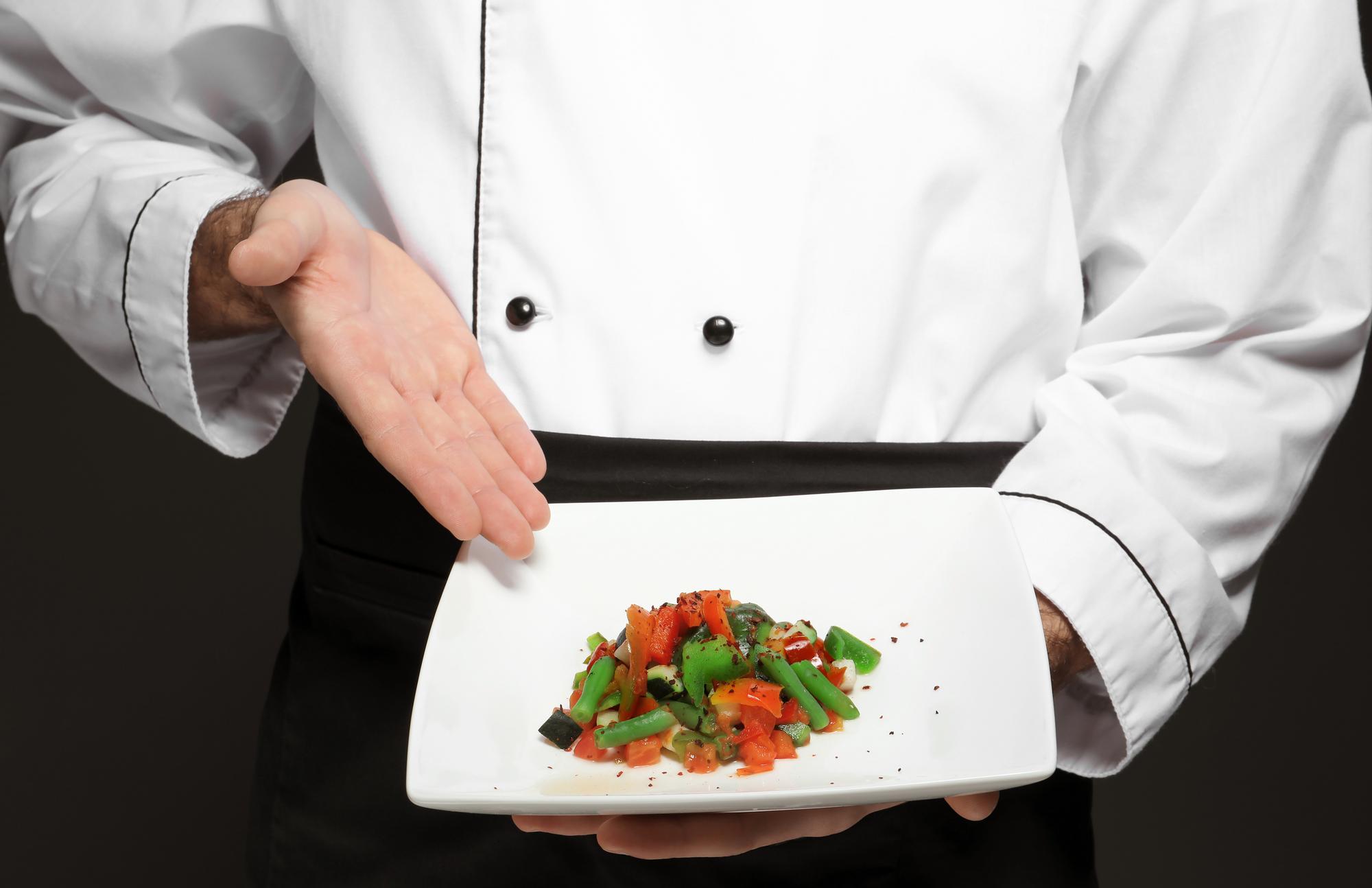 A professional plating demonstration with hands arranging food
